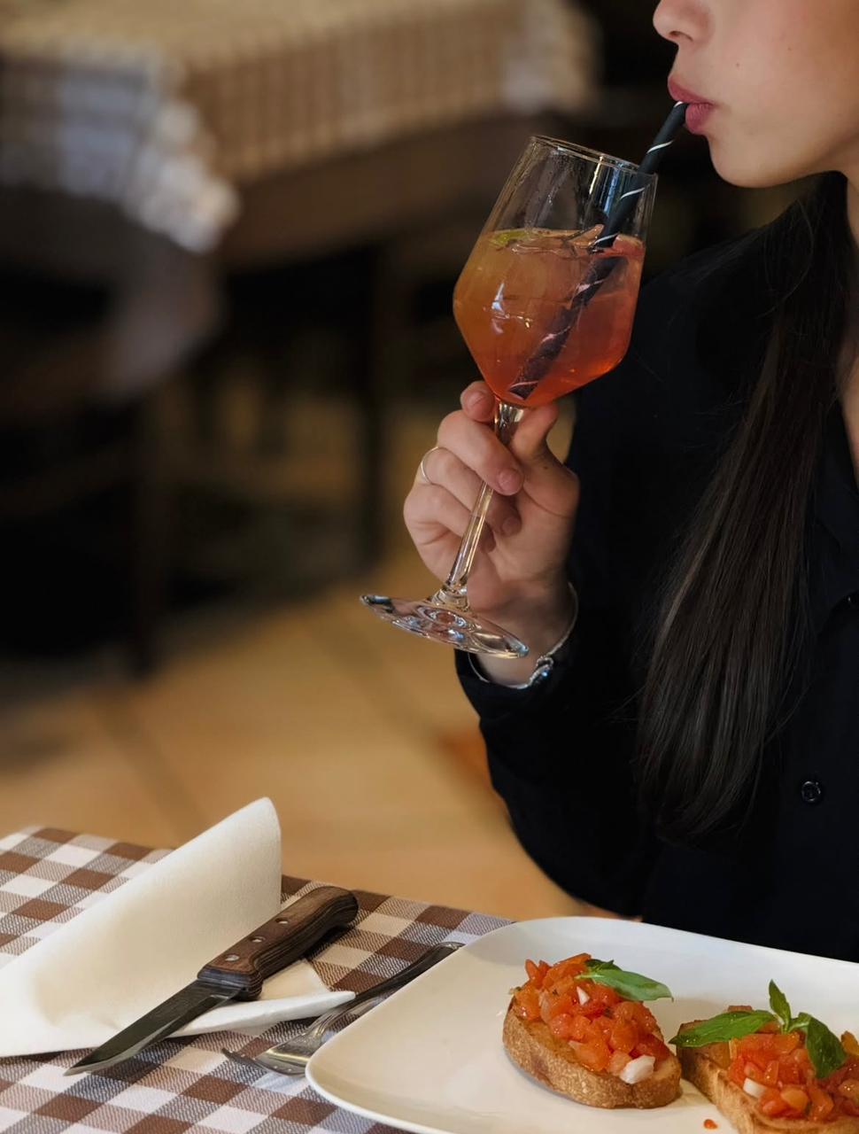 Gast mit Aperol Spritz und Bruschetta an gedecktem Tisch